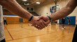 © Rohan Katwe - Two basketball players shake hands on indoor gym court, showing sportsmanship, teamwork and mutual respect after match. Blurred teammates and court lines highlight competition, training and community