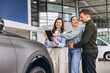 © anatoliycherkas - Saleswoman explaining car features on tablet to happy couple buying vehicle in modern auto showroom