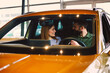 © djile - Happy couple sitting in new car at dealership showroom