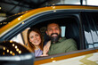 © djile - Smiling couple looking at camera from inside new vehicle