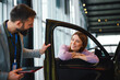 © djile - Woman talking with car salesman in showroom