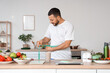 © Pixel-Shot - Sporty young man with fresh vegetables, smoothie and vitamins measuring his waist in kitchen. Healthy food concept