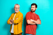© deagreez - Two men pose back to back in casual outfits against teal background