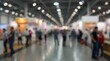 © Alex Pios - Blurred indoor exhibition hall filled with people walking through exhibit booths and bright lights
