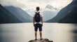 © xio - Man overlooks lake and mountain range during outdoor adventure travel concept
