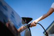 © DZ FILM/Stocksy - A woman connects the charger to an electric car