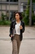 © Studio Sincère/Stocksy - Business Professional Walking Outdoors With Laptop and Coffee Cup