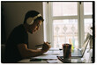 © ByLorena/Stocksy - Young Man Studying at a Desk With Headphones in Bright Room
