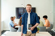© Santi Nuñez/Stocksy - Smiling businessman holding tablet with coworkers in office
