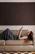 © Asya Molochkova/Stocksy - Woman Lounging on Sofa While Browsing Smartphone