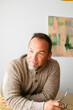 © ByLorena/Stocksy - Man in Sweater Sits at Table With Thoughtful Expression