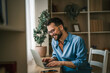 © Miljan Živković - Man working from home on laptop, telecommuting smiling