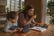 © Miljan Živković - Mother and daughter multitasking during remote work and breakfast