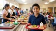 © ViskBx - Happy elementary school boy holding a healthy lunch tray in a busy cafeteria line, smiling at camera