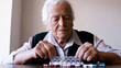 © Tati - An elderly person organizes their medication into a weekly pill dispenser.