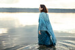 © Anna Artemenko/Stocksy - woman in blue dress by the water at sunset