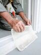 © Ryzhkov - Professional Repairman Holding White Mosquito Net for Window Installation and Home Maintenance Services, Close Up of Skilled Craftsman Hands Working with Plastic Frame