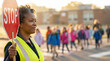 © ViskBx - African american school crossing guard with stop sign, children in background, school safety