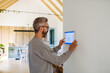 © Halfpoint - Man using smart home control panel.