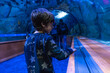 © unai - Young boy exploring underwater tunnel at aquarium looking at fish