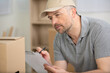 © auremar - delivery man with cardboard boxes writing on clipboard