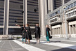 © wavebreak3 - Four female graduates wearing gowns standing on plaza throwing caps while sun casting tiled shadows