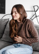 © luciano - Young and beautiful sick woman sits at home clutching her aching stomach, suffering from abdominal discomfort caused by indigestion, gastritis, menstrual cramps, or digestive problems, cramps