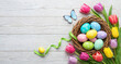 © Neo GT - Easter background. Colorful spring tulips with butterflies and painted eggs on a wooden background with copy space, top view