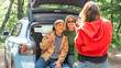 © olezzo - Adult daughter taking photo of her senior mother and sister sitting in open car trunk