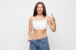 © ViDi Studio - Slender young woman with slim fit body wear lingerie underwear pull jeans slightly down showing toned waist after weight loss isolated on plain solid white background studio. Lifestyle diet concept.