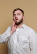 © bodnarphoto - Surprised man with a shocked expression touching his face against a light brown background