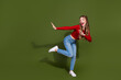 © deagreez - Young woman in red top and jeans leaps with energy against green background for lifestyle fashion advertisement