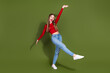 © deagreez - Young woman in red top jeans leaps with joy on green studio background