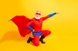 © deagreez - Elderly superhero man in red suit and cape strikes dynamic pose against bright yellow background