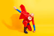 © deagreez - Brave senior superhero with red cape strikes a dynamic pose in a bright yellow studio background