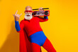 © deagreez - Energetic bearded senior in red and blue superhero costume with cape dances with a boombox on bright yellow background