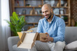 © Liubomir - Cheerful customer receiving and unboxing a delivery package from an online store, a joyful e-commerce shopping experience at home, sitting on a comfortable sofa