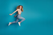© deagreez - Young stylish woman jumps against blue background wearing jeans and crop top for a fashion lifestyle stock photo