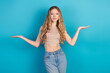 © deagreez - Young chic model in checkered crop top and jeans posing with open arms against blue background