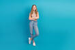 © deagreez - Young woman stands against blue background wearing jeans and a checkered top smiling with arms crossed for a fashionable stock photo