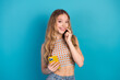 © deagreez - Young chic fashion model with a checkered top smiling holding a yellow phone against a blue background