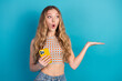 © deagreez - Young stylish woman with blonde hair holds yellow smartphone and gestures against a blue backdrop