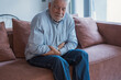 © Daniel - One old man feeling bad and suffering stomachache at home sitting on sofa massaging and touching belly.