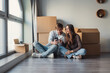 © Daniel - A young couple sits in their renovated living space surrounded by relocation boxes, reflecting on new beginnings and dreaming about a cozy and stylish interior