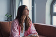 © Daniel - Close-up of a sad millennial woman sitting alone at home, lost in thought about relationship problems and personal struggles, expressing loneliness, emotional pain, and quiet reflection