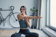 © Daniel - A young woman performs stretching movements in a comfortable living room, improving mobility and body control as part of a balanced home workout and wellness-focused lifestyle