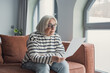 © Daniel - Focused elderly 60s woman sit on sofa in living room reading postal correspondence or bank notice, concentrated mature 50s female rest on couch at home consider message in paper post letter