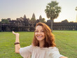 © Buyanskyy Production - Happy Woman Taking Selfie and Pointing at Angkor Wat Temple in Cambodia