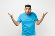 © khosrork - Portrait of unshaven man wearing blue T- shirt standing spreads palms, looks astonished at camera, quarrels with someone feels puzzled. Indoor studio shot isolated on gray background.