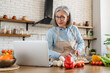 © InsideCreativeHouse - Smart eating. Confident senior woman wife using laptop online app website to find healthy salad recipe search meal idea online in culinary blog when cooking natural vegetable food at home kitchen.